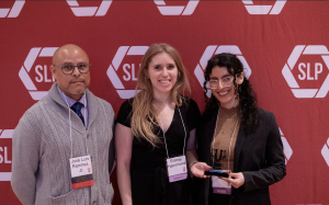 Two women and one man in front of a red backdrop.